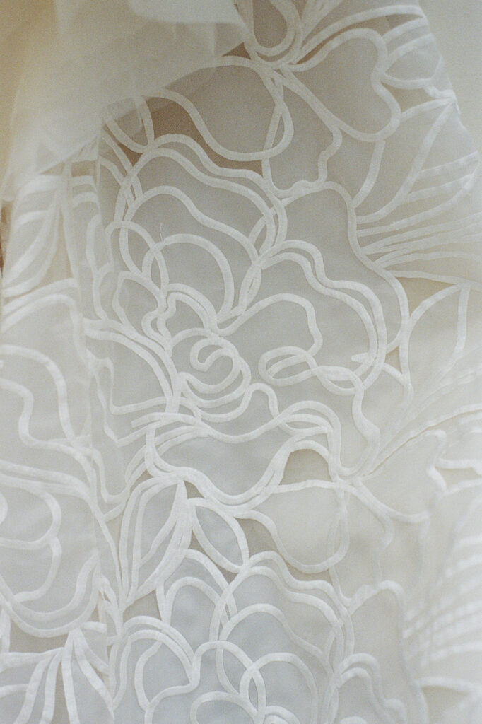 Sheer white fabric with delicate embroidered floral pattern.