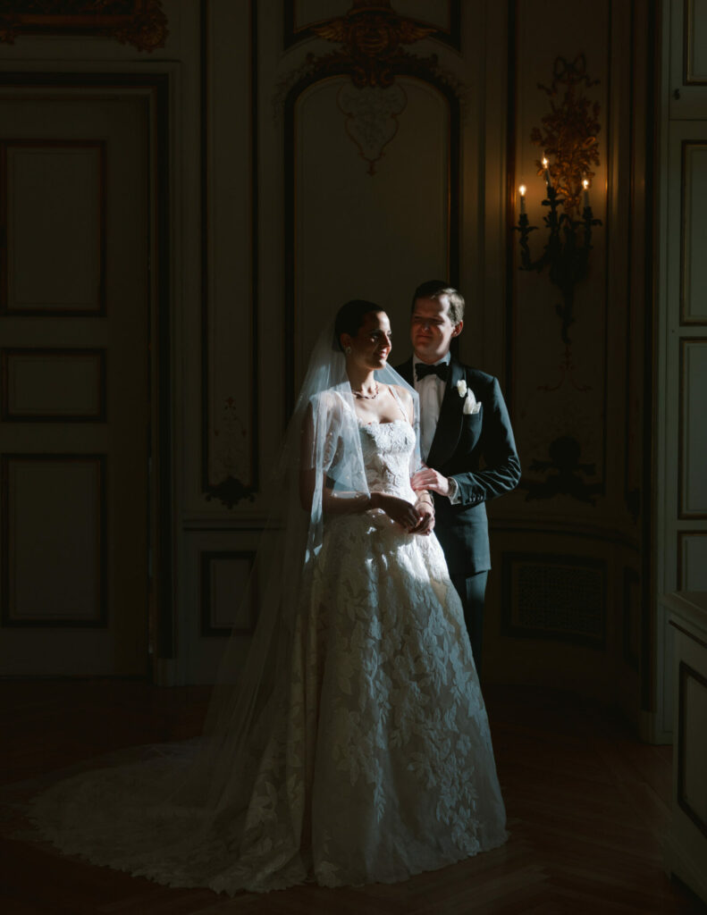 Bride in couture gown and groom in elegant room.