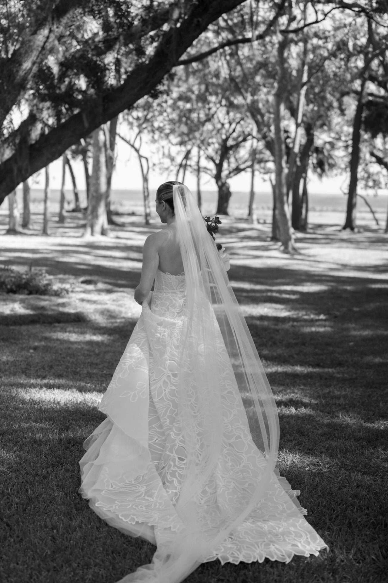 Bride in strapless dress, long veil, walks away.