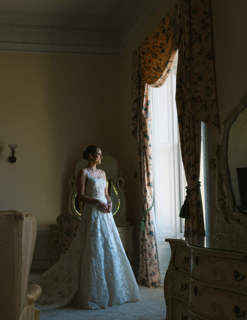 Katya Ruiz in luxury gown by ornate floral window.