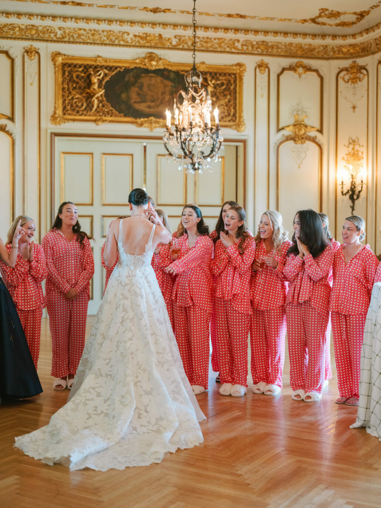 Bride in couture dress, bridesmaids cheer in pajamas.