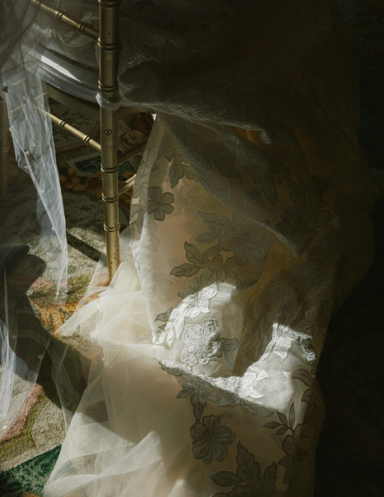 Sheer floral fabric on gold chair, sunlight casting shadows.