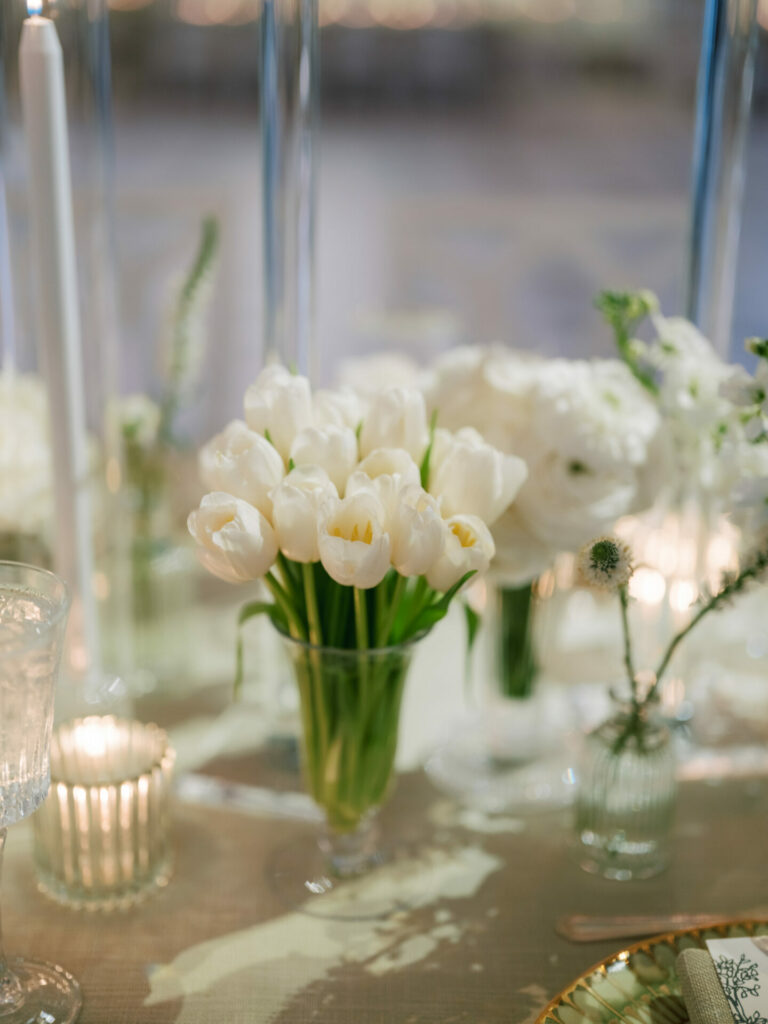 Elegant white tulips centerpiece with candles, glassware.
