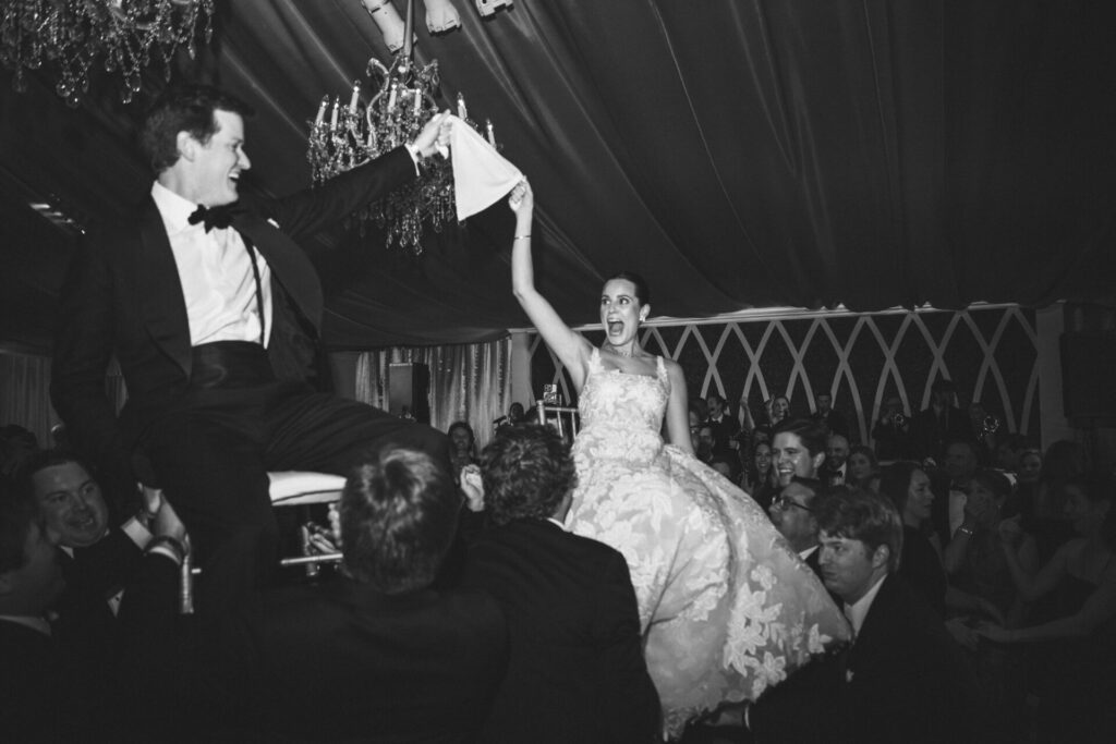 Katya Ruiz and groom lifted on chairs, celebrating.