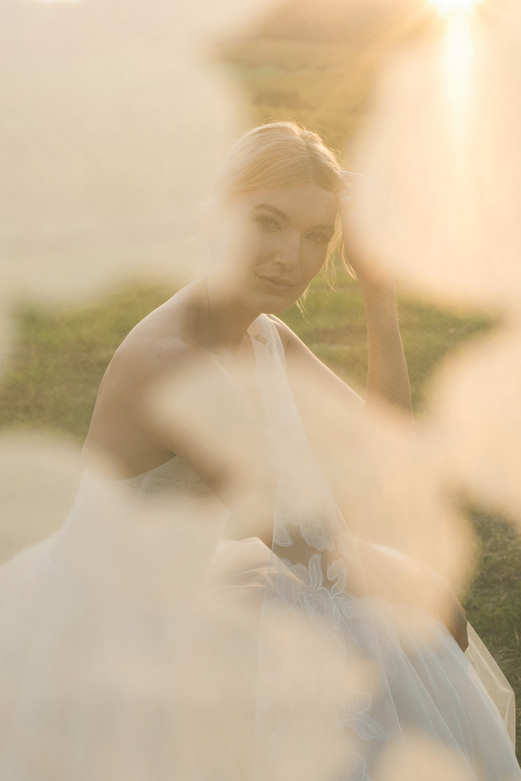 Woman in white dress sits in dreamy sunlight.