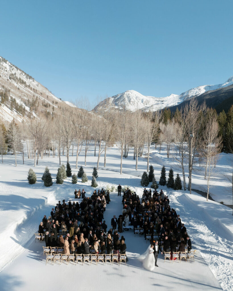 Winter wedding in snowy mountains under blue sky.