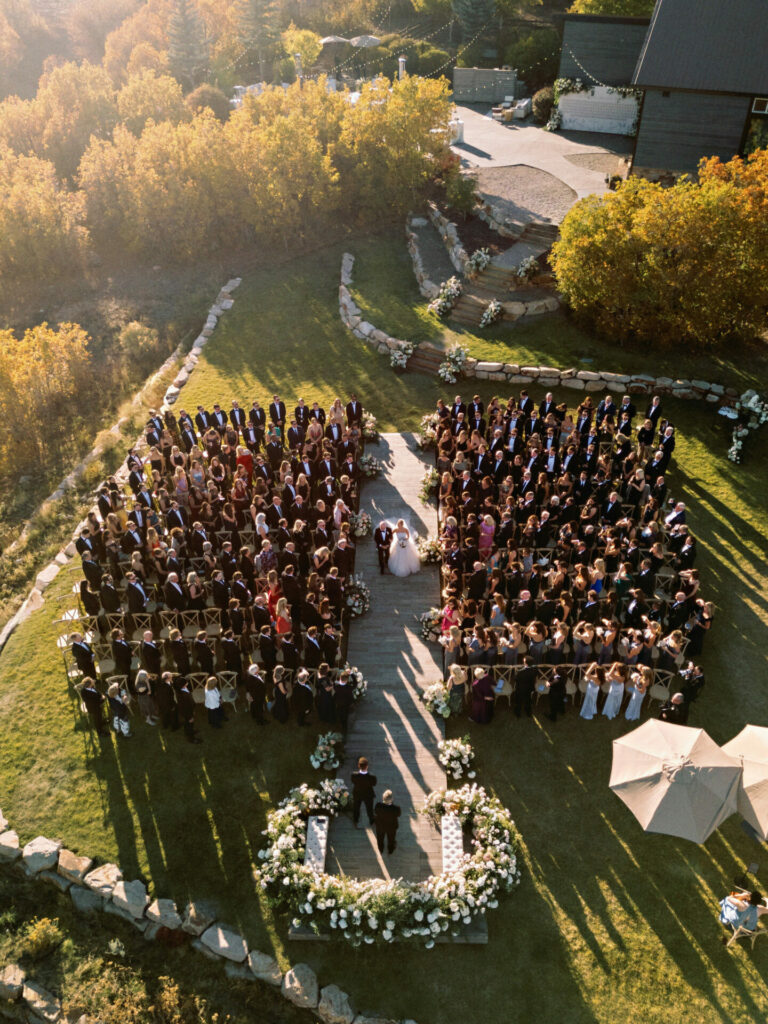 Aerial view: Outdoor wedding, guests in square, floral altar.
