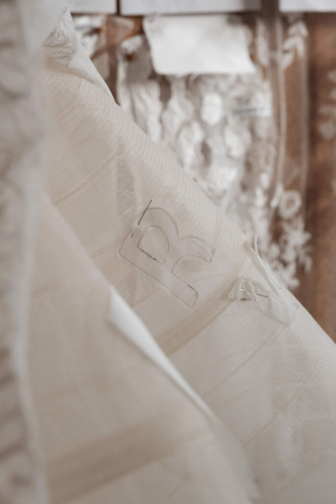 Sheer fabric with "BC," lace swatches blurred behind.