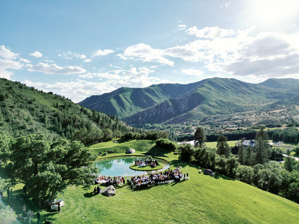 Dreamy hillside wedding by pond, trees, and sunlight.
