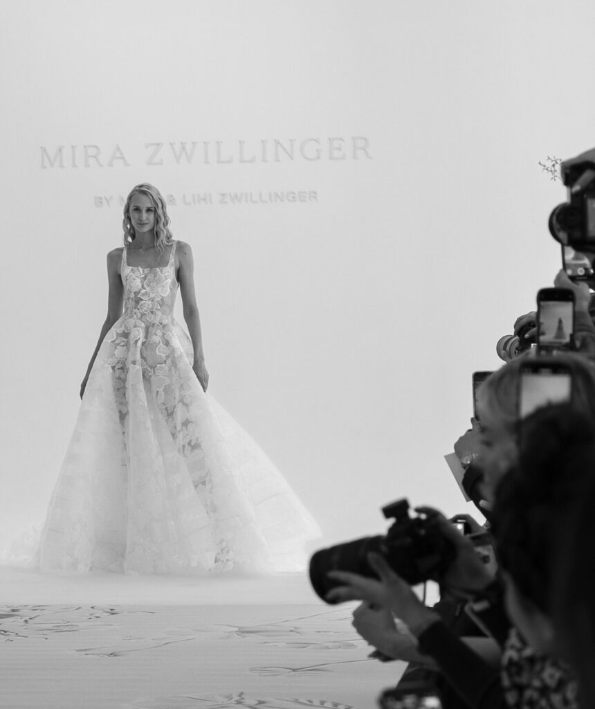 Model in floral wedding gown on black-and-white runway.