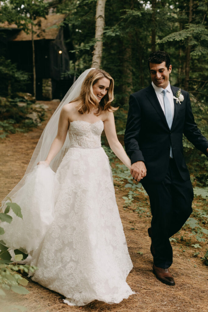 Bride and groom smiling, walking hand in hand.