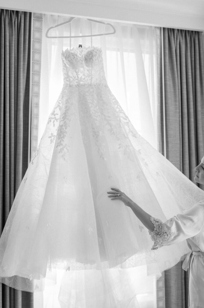Person in robe reaches for wedding dress, anticipating.