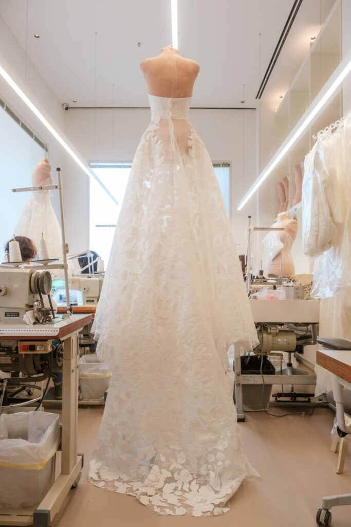 Floral white wedding gown on dress form in atelier.