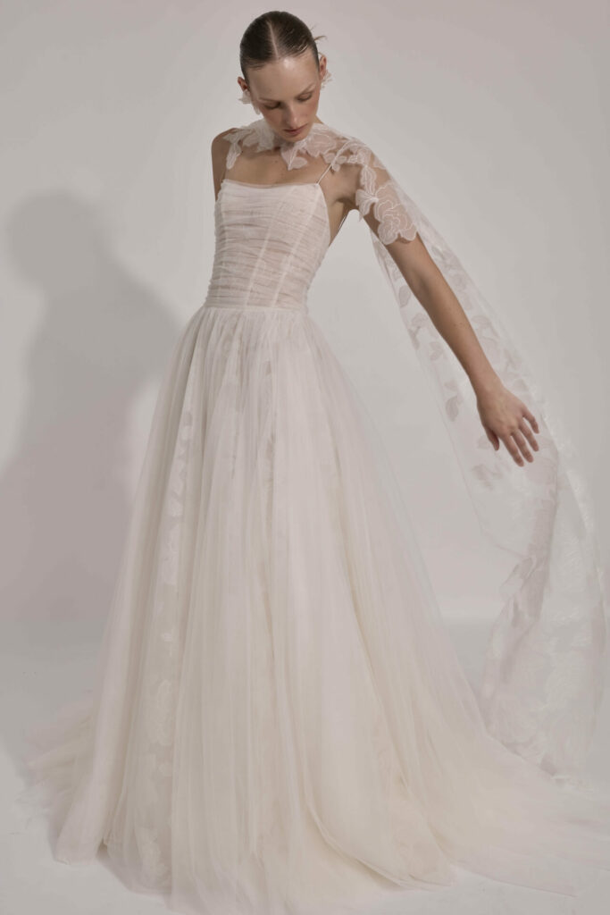 Woman models sleeveless white tulle wedding gown.