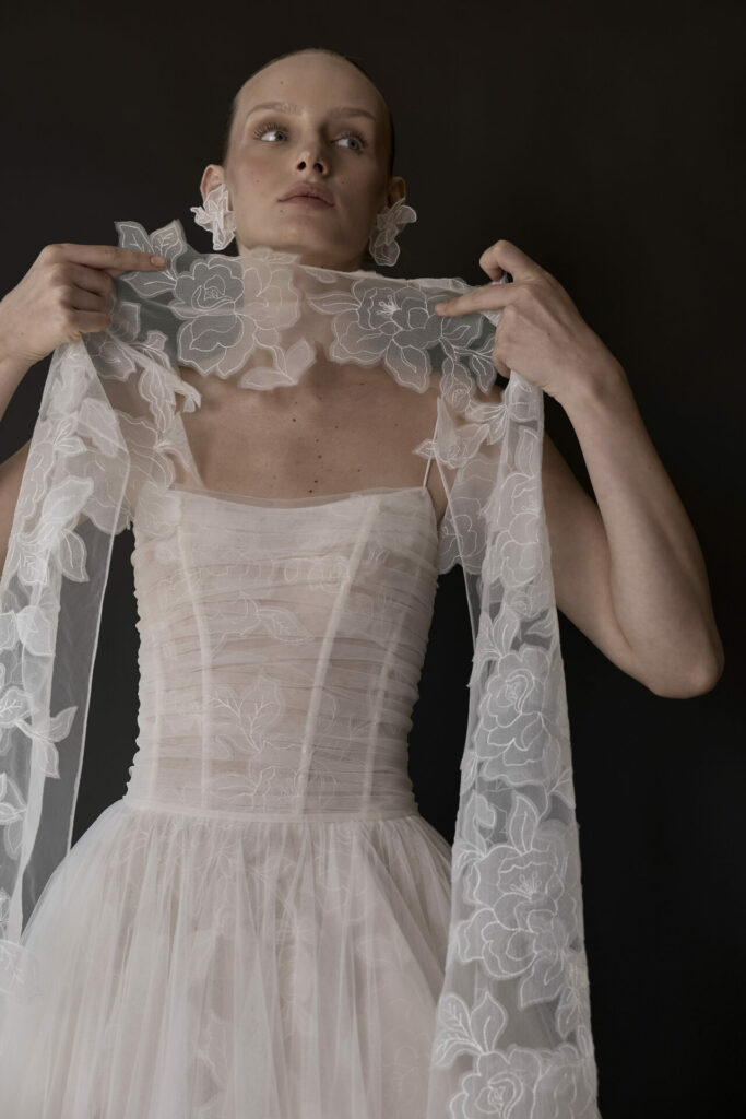 Person in sheer floral lace dress with scarf.