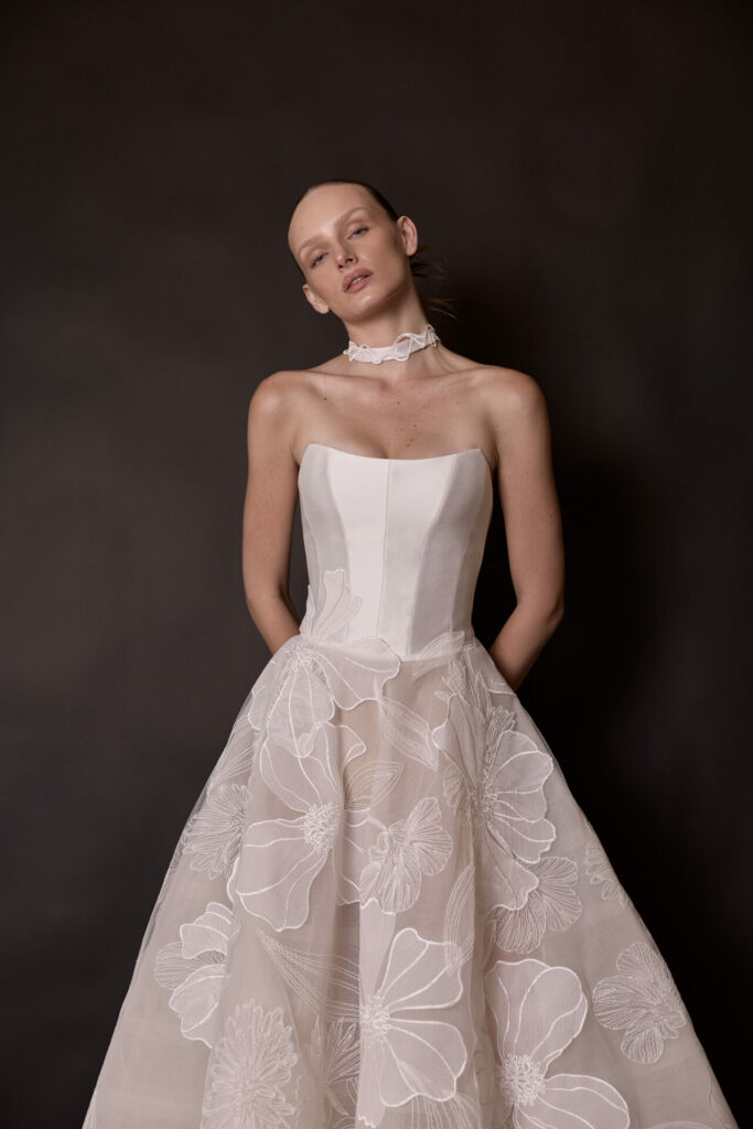 Woman in strapless floral white dress, hands hidden.