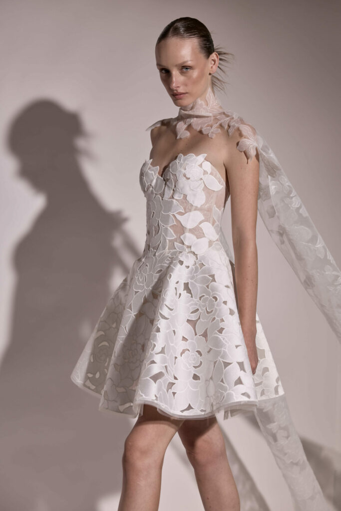 Woman in white lace dress with sheer cape.