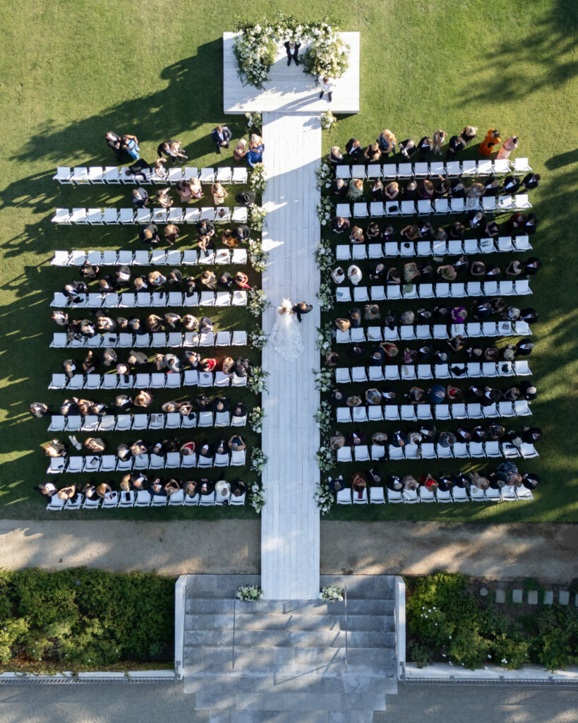 Outdoor wedding, guests seated, couple near flowered altar.
