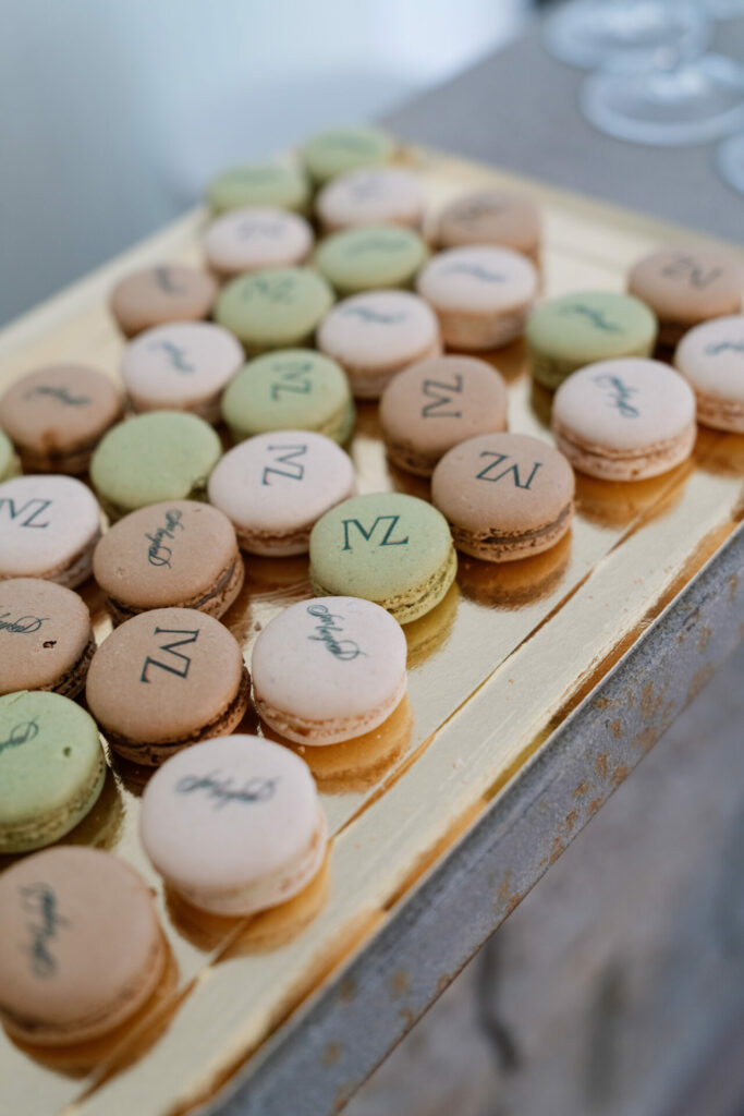 Pastel green, brown, beige macarons with gold tray and writing.
