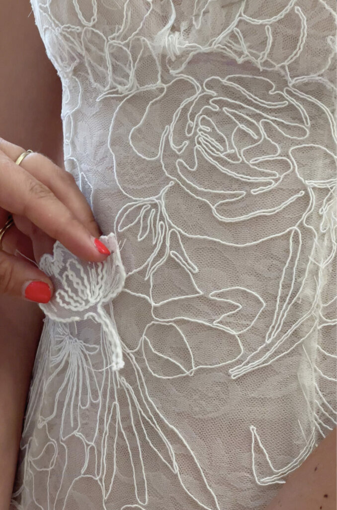Hand with red nails, gold rings, holding floral lace.