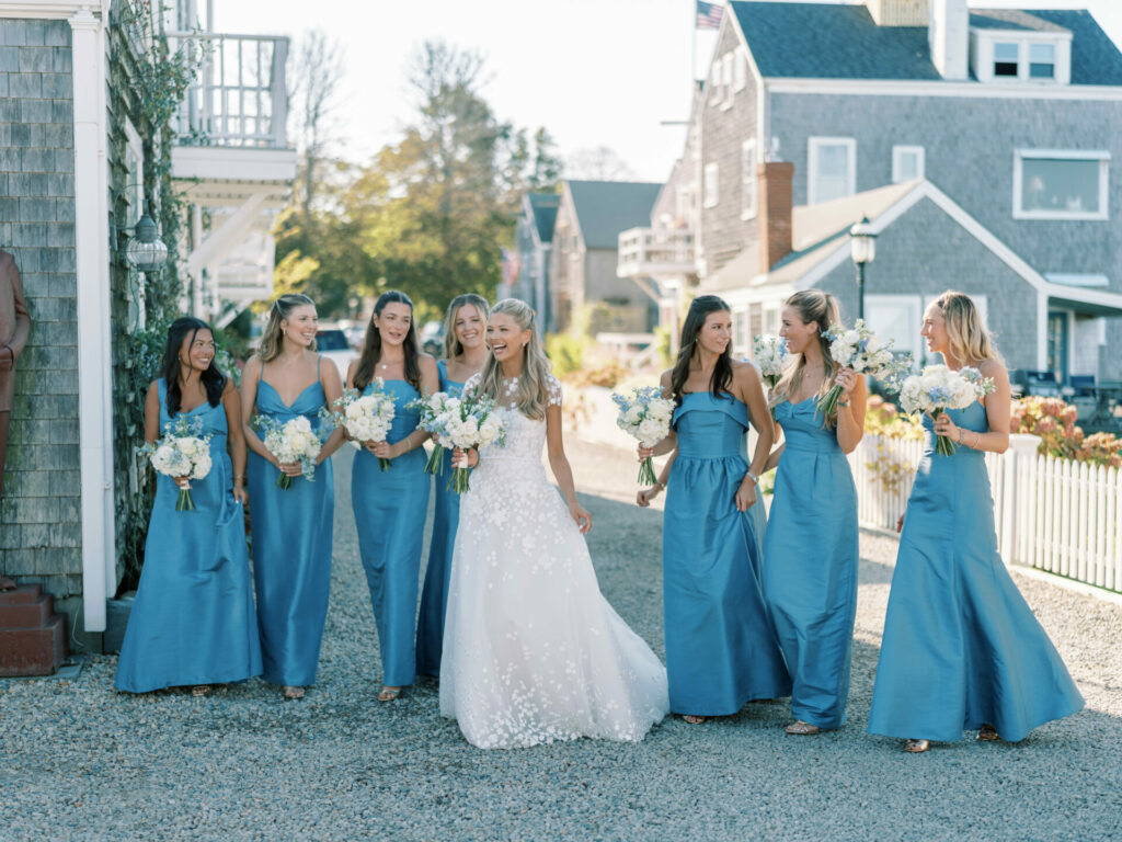 Katya Ruiz and six bridesmaids smiling outside in gowns.