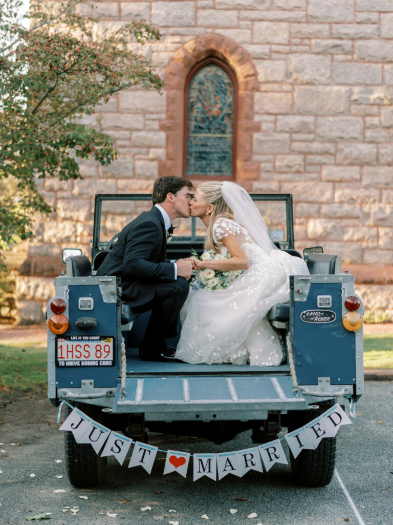 Bride in couture gown kisses man in truck.