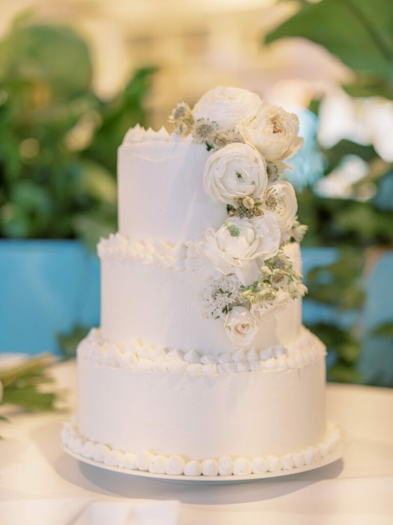 Elegant white tiered cake with roses and greenery.