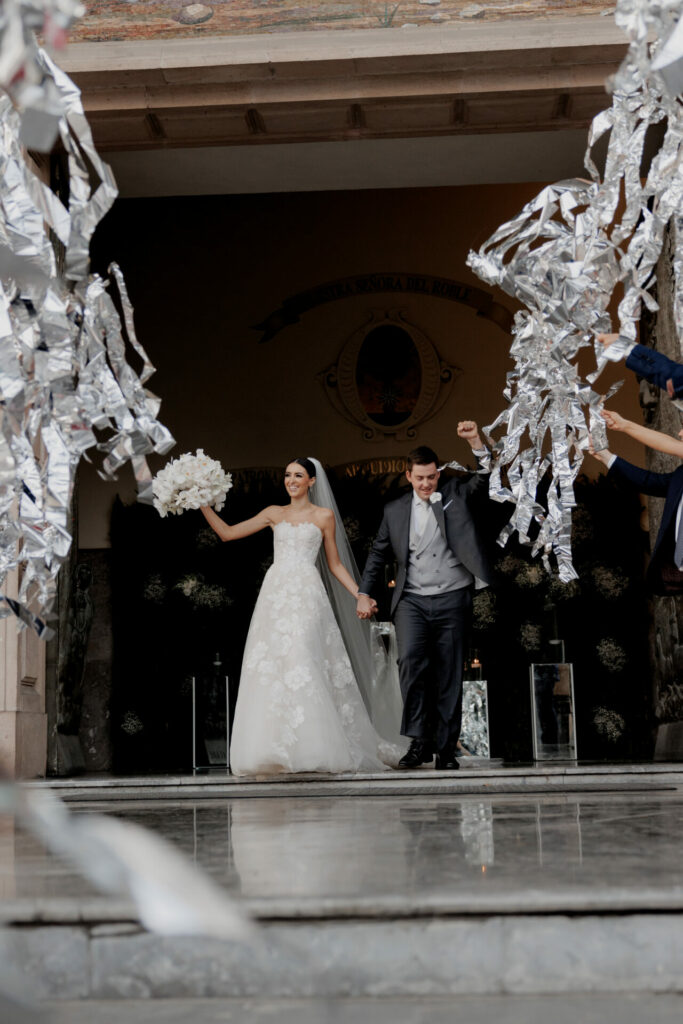 Bride Katya Ruiz and groom exit, guests wave streamers.