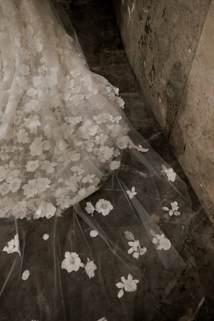 Sheer Mira Zwillinger gown train with floral appliqués.