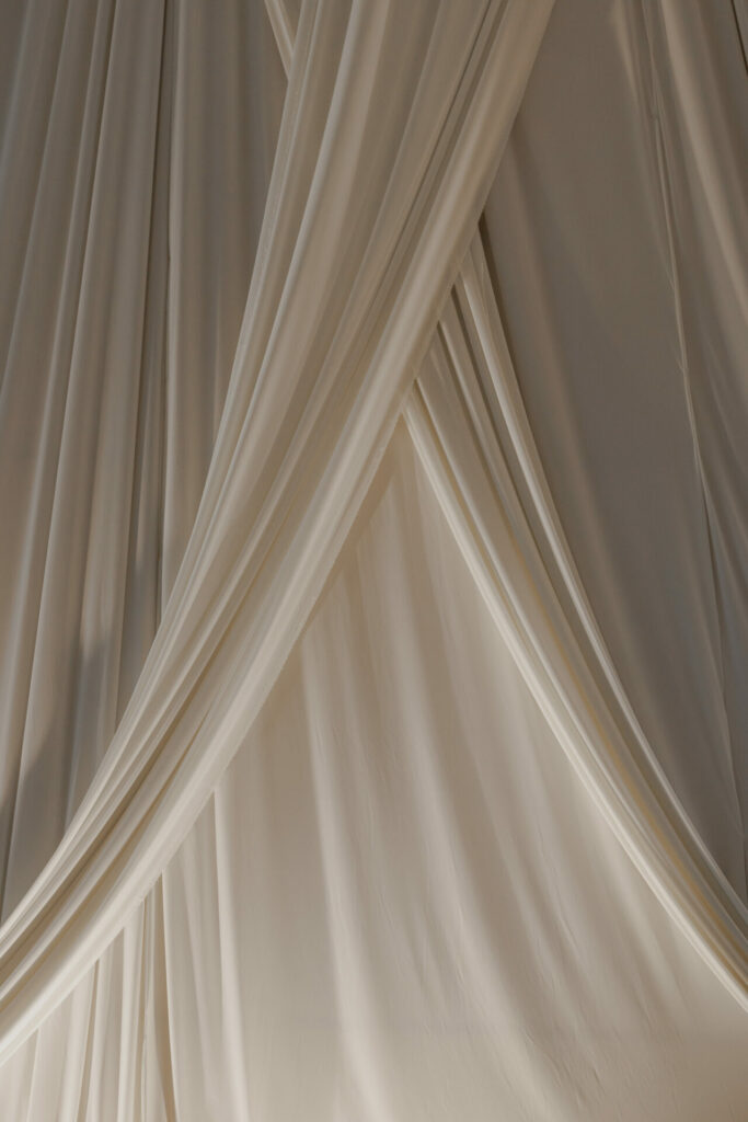 Cream drapes in soft folds, luxury minimalist backdrop.