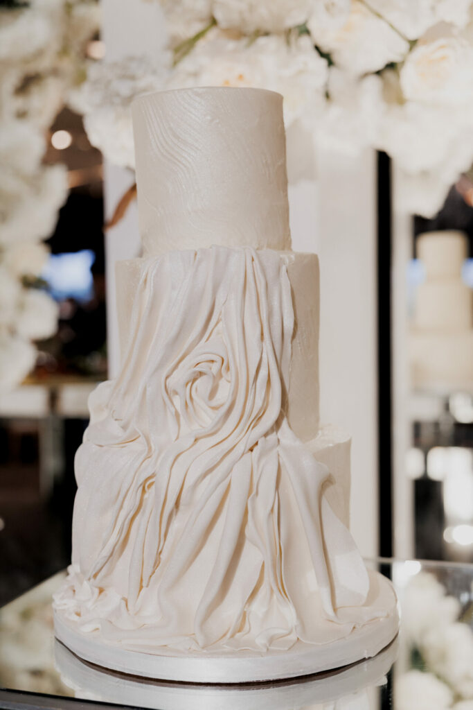 Elegant white three-tiered couture cake with cascading roses.