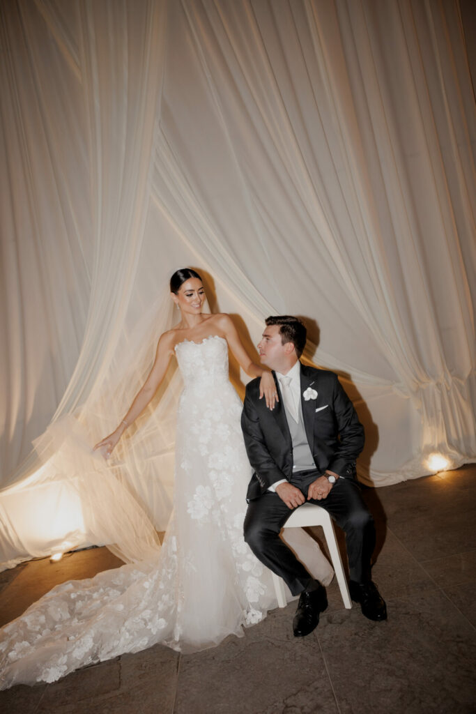 Katya Ruiz in floral lace gown beside groom, smiling.