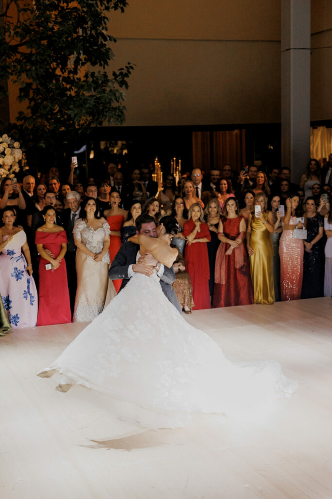 Bride in flowing gown lifted by groom during first dance.