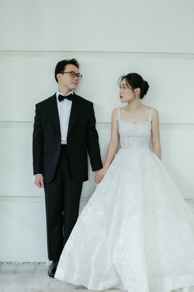 Katya Ruiz and groom hold hands, elegantly posed in couture.