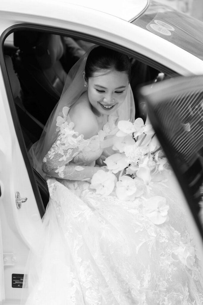 Bride in elegant gown, stepping from car, smiling.