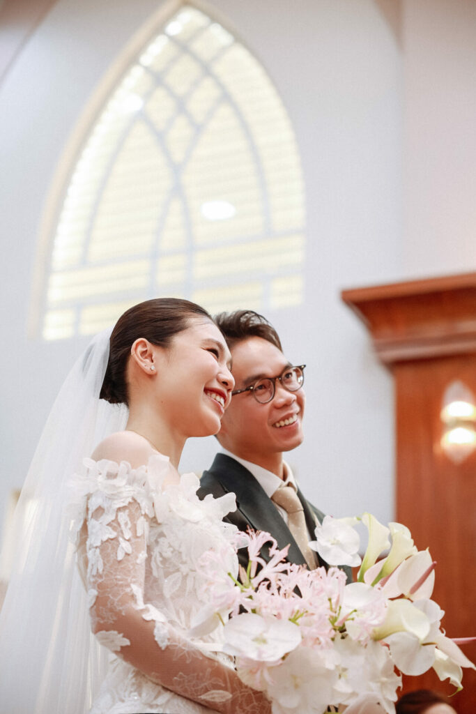 Katya Ruiz smiles with groom, bouquet in sunlight.