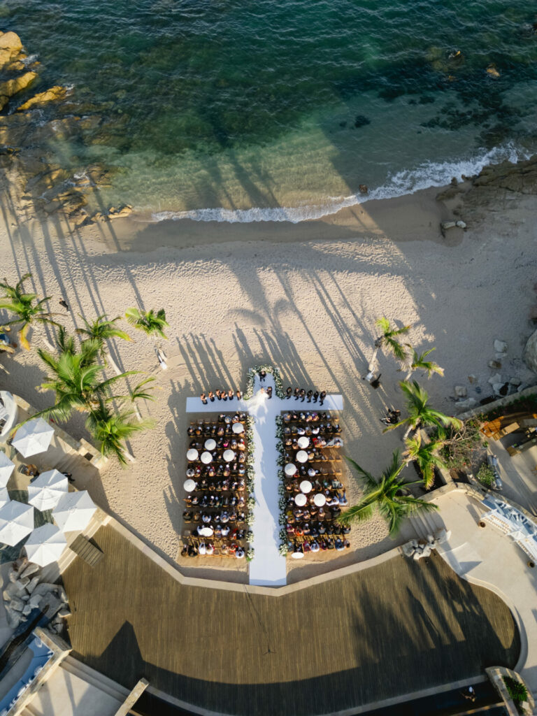 Bride Katya Ruiz at beach wedding, guests seated, palm shadows.