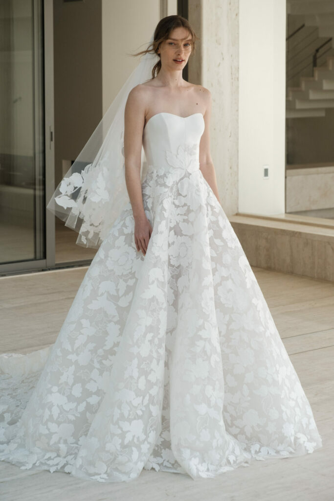 Bride indoors in strapless floral Ness & Nessia gown.