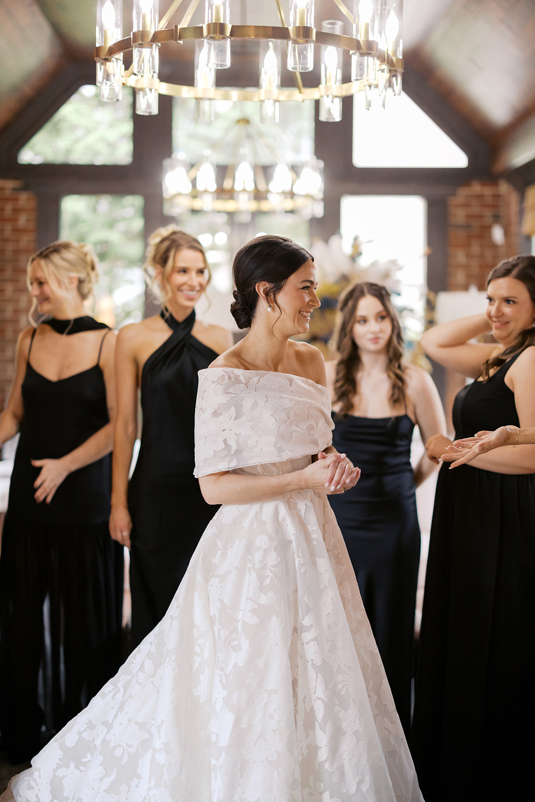Bride twirls in white gown, bridesmaids in black.