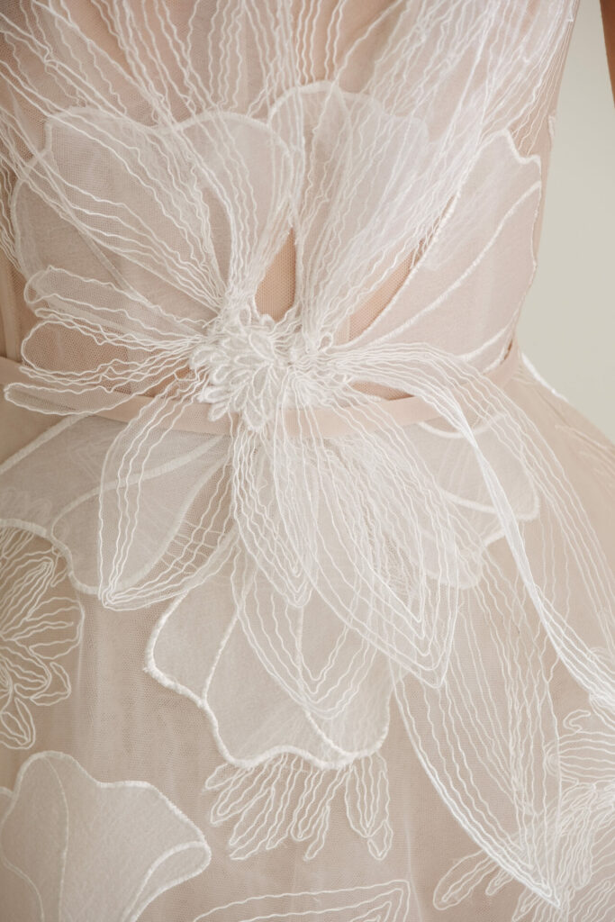 Sheer nude fabric with white floral embroidery.