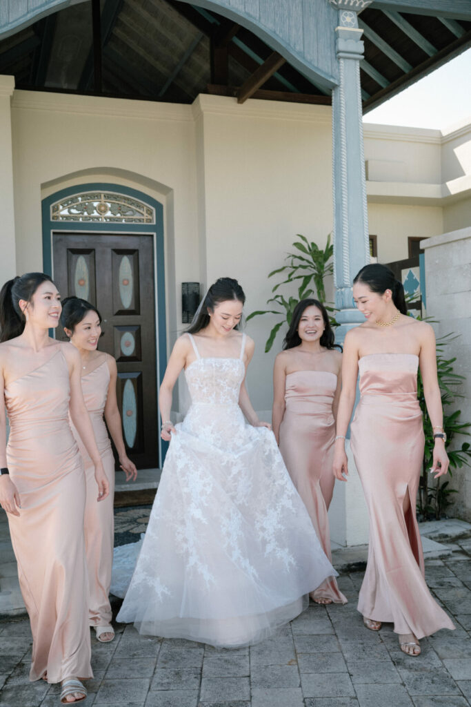 Smiling bride with four bridesmaids in pink dresses outside.