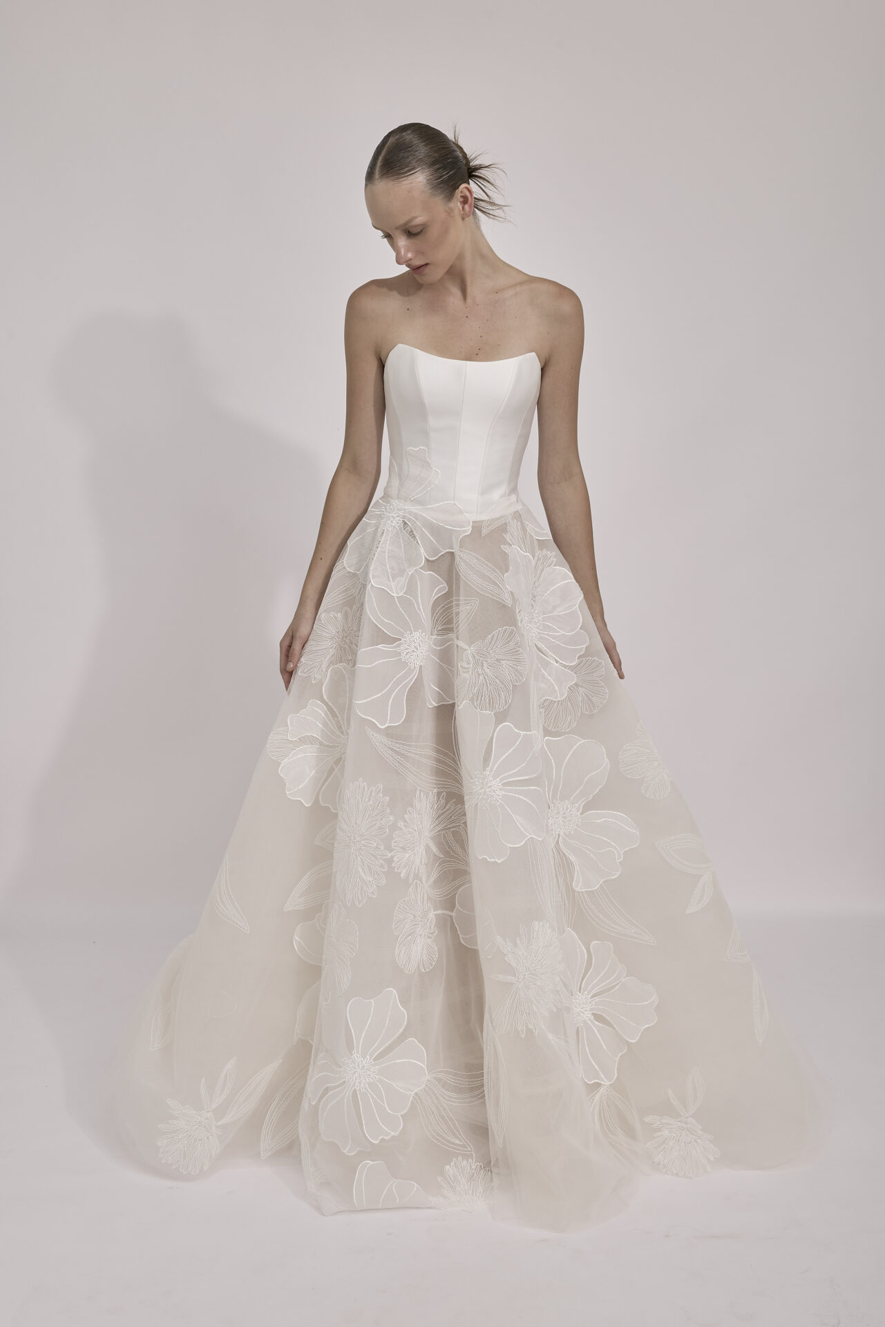 Woman in floral strapless wedding gown looking down.