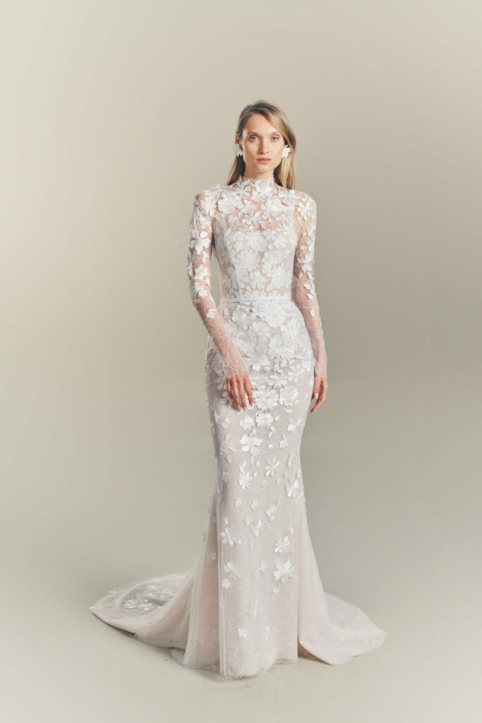 Woman in fitted white lace gown with appliqués.