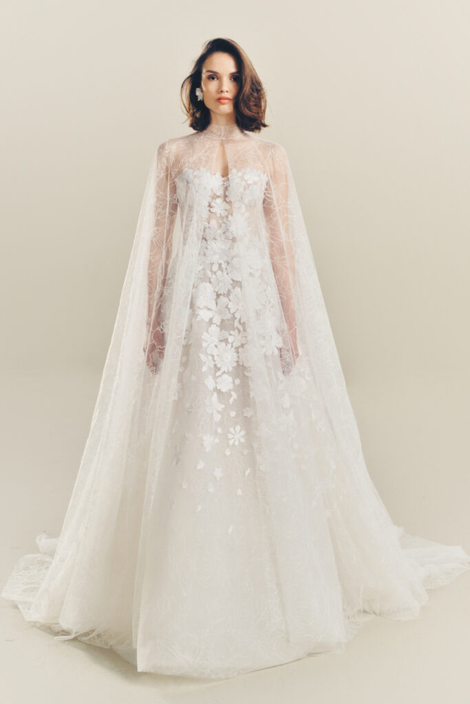 Woman in white lace gown with long sheer cape.