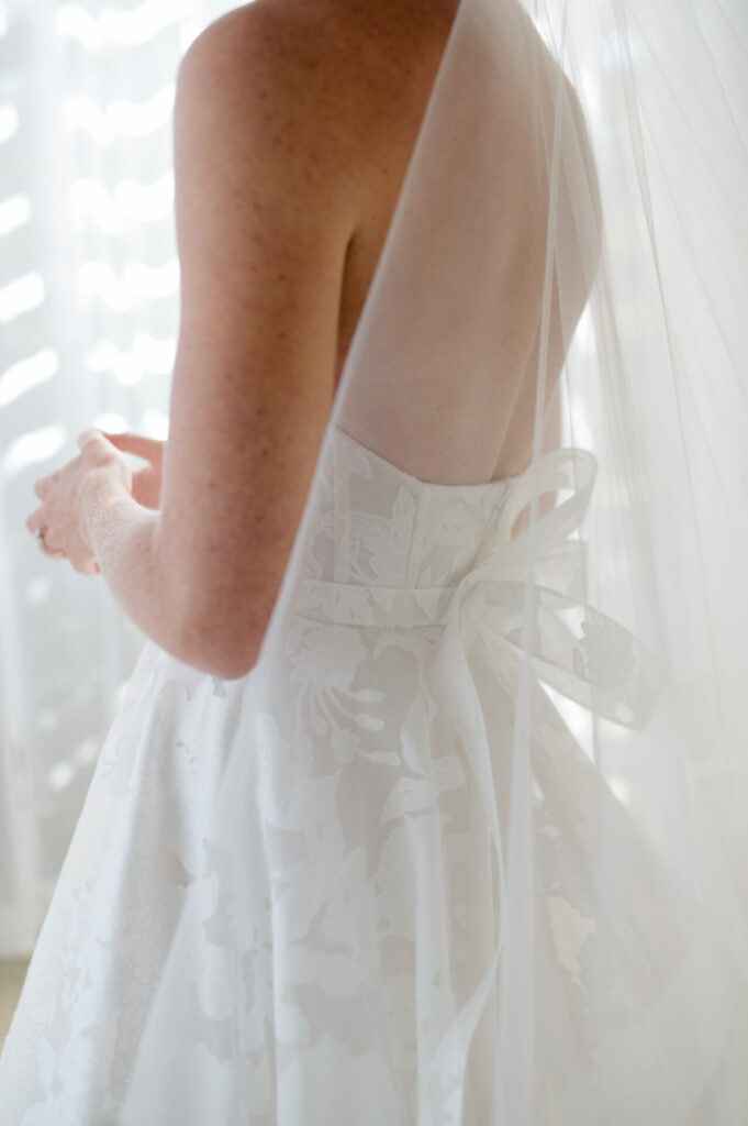 Katya Ruiz in floral Mira Zwillinger gown, ribbon waist, soft veil.