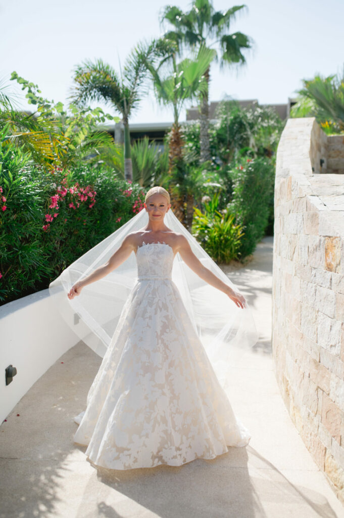 Katya Ruiz in strapless white gown on sunny garden path.