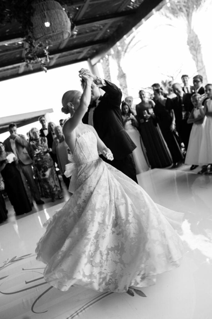 Bride and groom dance; guests watch, luxury scene.