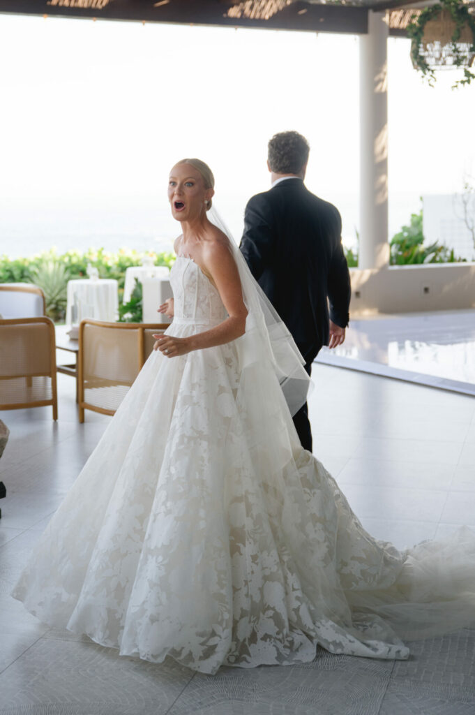 Katya Ruiz in strapless gown, surprised as groom turns away.