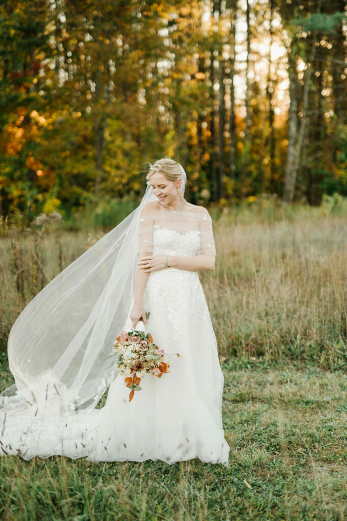 Bride in A-line gown, autumn bouquet, sunlit field.