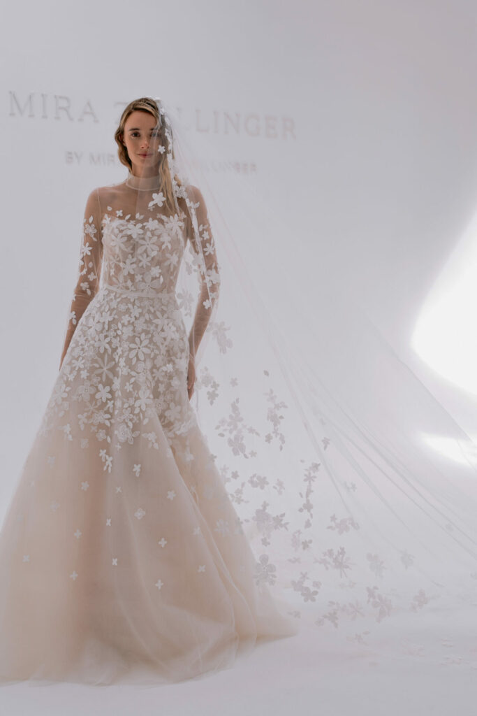 Bride in sheer floral wedding gown and veil.